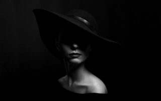 Een knappe dame met een donkere achtergrond en opgelicht gezicht. Het perfecte model voor zwart wit fotografie.