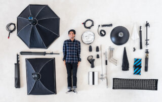 Een man die op de grond ligt met allerlei fotografie accessoires om hem heen.