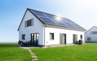 Een woningfotograaf heeft een foto genomen van een vrijstaande witte woning met zonnepanelen op het dak, waarbij de moderne en milieuvriendelijke aspecten van het huis in beeld worden gebracht.