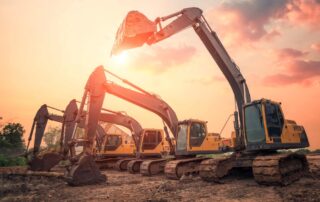 Vier graafmachines op een bouwplaats die geparkeerd staan.