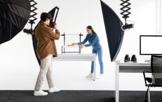 Een vrouwelijke productfotograaf plaatst zorgvuldig een product op zijn plaats en neemt een foto, wat het proces illustreert van het creëren van professionele productfoto's met aandacht voor compositie en presentatie.
