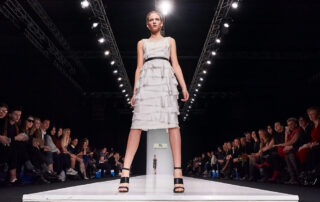 De ultieme runway fotografie foto van een model die op de voorgrond van een modeshow staat.