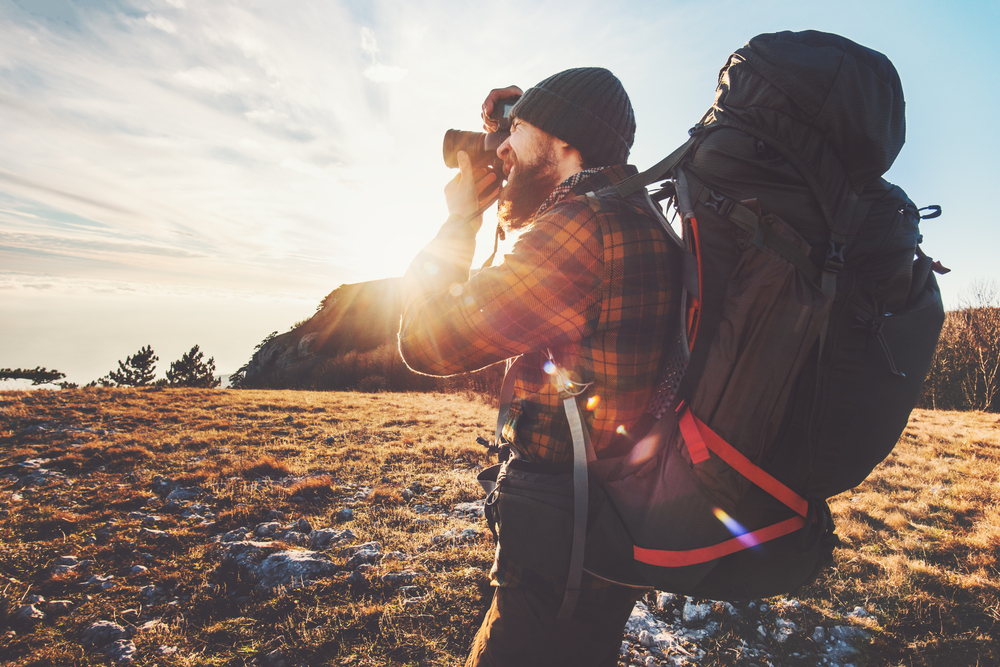 Een reisfotograaf, met een rugzak op zijn rug en camera in de hand, staat klaar om op avontuur te gaan en de wereld vast te leggen, belichaamt de geest van reisfotografie en ontdekking.