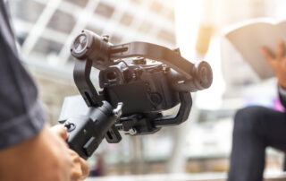 Een man staat buiten en houdt een camera vast die is bevestigd aan een stabilisator. De stabilisator is een apparaat dat is ontworpen om cameratrillingen te minimaliseren. De man is actief bezig met het vastleggen van beelden in de buitenlucht, en de stabilisator helpt hem om schokvrije en professioneel uitziende opnamen te maken, zelfs in een dynamische buitenomgeving. Dit essentiële hulpmiddel zorgt voor vloeiende beelden en maakt het mogelijk om de schoonheid van de natuur op indrukwekkende wijze vast te leggen.