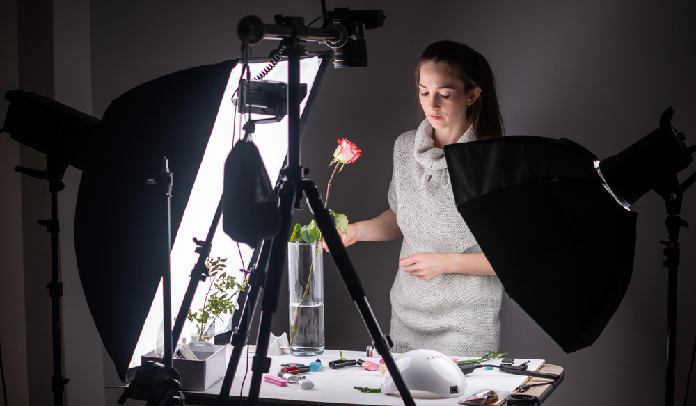 Een fotograaf gebruikt een softbox om een foto van een roos te maken in een donkere omgeving. De softbox zorgt voor een zachte en evenwichtige belichting van de roos, waardoor de details en kleuren prachtig worden vastgelegd, zelfs in het donker. Dit creëert een betoverende en sfeervolle foto.