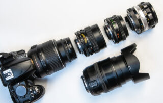 Een compositiefoto met een camera en verschillende soorten zoomlenzen op een tafel. De camera staat centraal in de compositie, omringd door een assortiment zoomlenzen van verschillende brandpuntsafstanden. Deze opstelling illustreert de flexibiliteit van de camera en benadrukt de keuzemogelijkheden die fotografen hebben om de juiste lens te selecteren voor verschillende fotografische situaties.