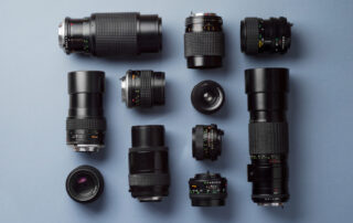 Een verzameling cameralenzen op een tafel geplaatst. De lenzen zijn zorgvuldig gerangschikt en staan klaar voor gebruik. Deze opname toont de verscheidenheid aan lenzen die beschikbaar zijn voor fotografen, variërend in brandpuntsafstanden en doeleinden. Fotografen kunnen kiezen uit deze assortiment lenzen om de juiste tool te selecteren voor hun fotografische behoeften.