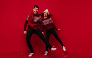 Man en vrouw dansend in een rode kerstsfeer tijdens een kerst fotoshoot, omgeven door kerstversieringen en warme verlichting.