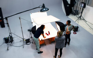Een groep mensen in een goed uitgeruste fotostudio die samenwerken om een product te fotograferen voor 'website foto's laten maken'. Deze foto laat zien hoe professionals in een studioomgeving productfotografie uitvoeren om hoogwaardige beelden te creëren die geschikt zijn voor gebruik op websites. Het benadrukt het proces van het laten maken van foto's voor online promotie.